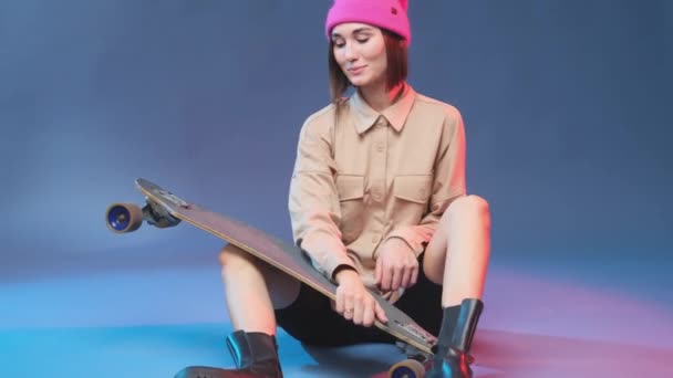 Chica positiva y elegante posa con skateborad en el estudio — Vídeos de Stock