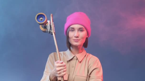 Pozitivní hipster dívka s skateboard nosí s růžovým kloboukem — Stock video