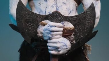 İki eli mavi arka planda baltasını tutan kötü kalpli kuzey Viking.