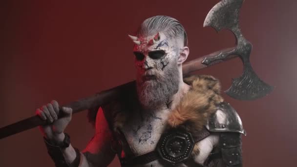 Guerrero demonio del norte con hacha enorme en su hombro en fondo rojo — Vídeos de Stock