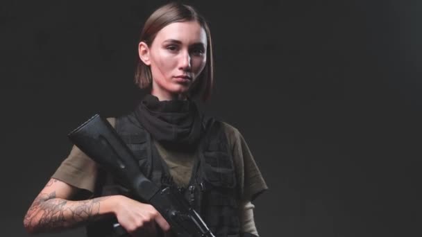 Armed with a rifle female soldier in dark background — Stock Video