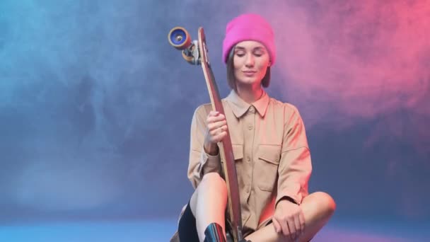 Charming female hipster poses with skate in smokey studio — Stock Video