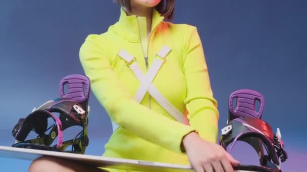 Kobieta model ubrany w żółtą odzież sportową gospodarstwa snowboard — Wideo stockowe