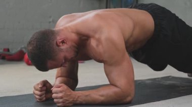 Spor salonunda kollarını yerde tutarak egzersiz yapan güçlü vücut geliştirici.