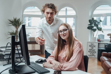 Kadın patron kameraya bakar ve meslektaşının yanındaki masada otururken gülümser.