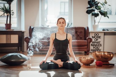 Kafkasyalı kadın Lotus 'ta meditasyon yaparken rahat bir dairede poz veriyor.