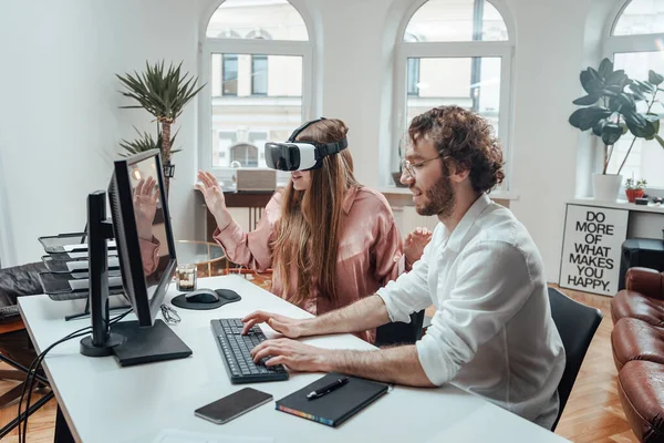 Женщина в очках виртуальной реальности и парень, печатающий на клавиатуре — стоковое фото
