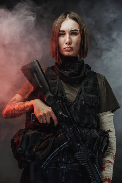 Fegyveres, vonzó nő, sötét háttérrel — Stock Fotó