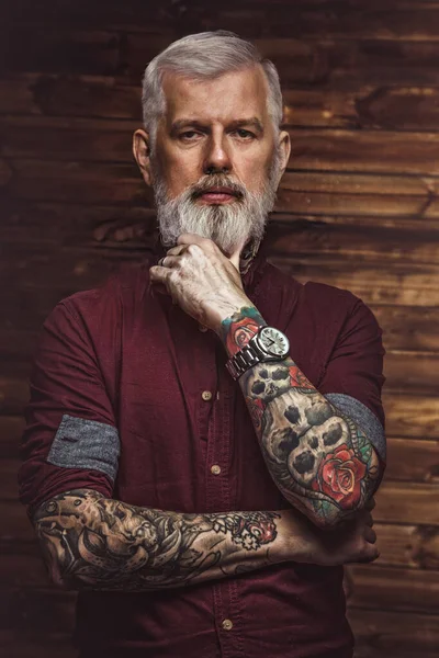 Grand-père dans un style rétro avec bras tatoués en fond de bois — Photo