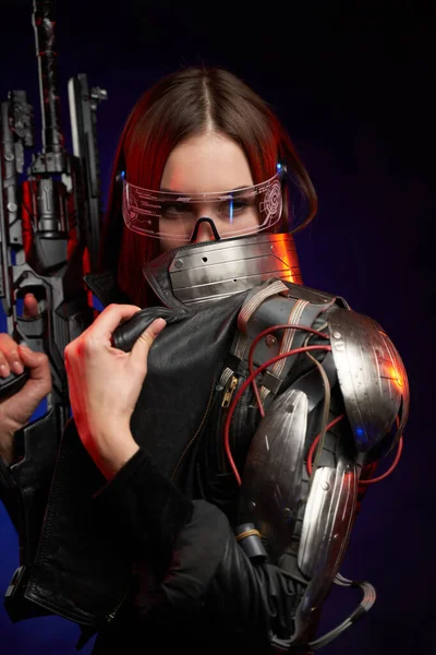 Mulher futurista com óculos e rifle em fundo azul escuro — Fotografia de Stock