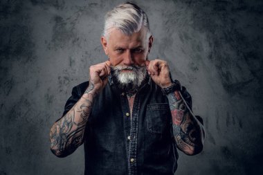 Eski tarz giyinen vahşi ve yaşlı motosikletçi koyu arkaplanda poz veriyor