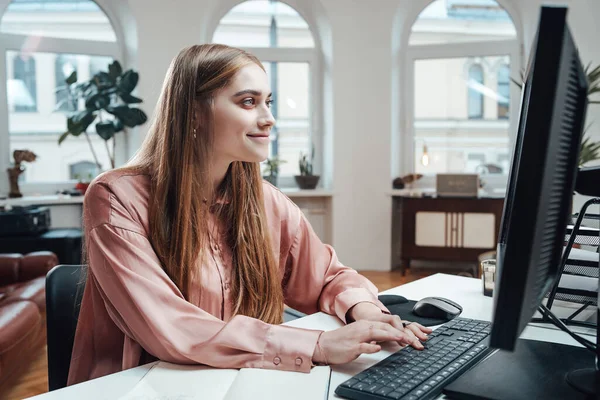 幸せな女性はオフィスのテーブルでコンピュータ上で動作します — ストック写真