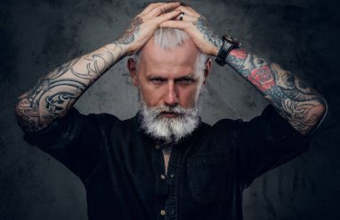 Eski tarz giyinen vahşi ve yaşlı motosikletçi koyu arkaplanda poz veriyor