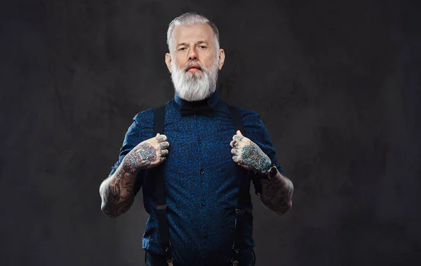 Confident and stylish old man in shirt poses in dark background