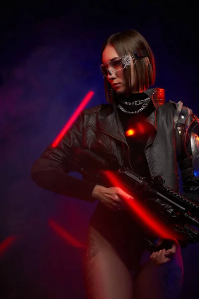 Cyber woman with rifle posing in dark background with lights — Stock Photo, Image