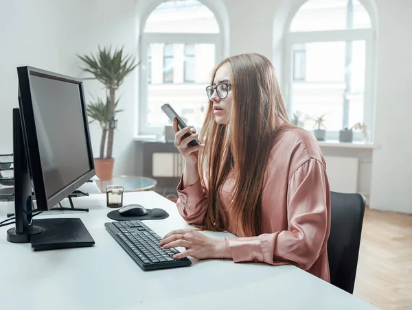Zakenvrouw met telefoon en computer in kantoorruimte — Stockfoto