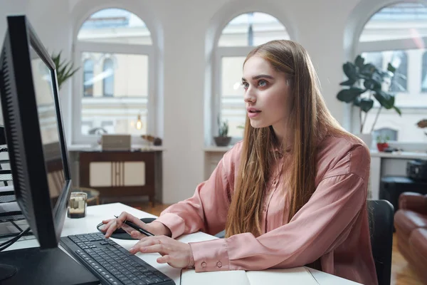 Vrolijke vrouw werkt op de computer aan tafel in het kantoor — Stockfoto