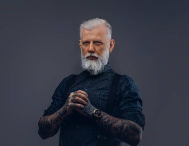 Kendinden emin büyükbaba karanlık arka planda poz veren kameraya bakar.