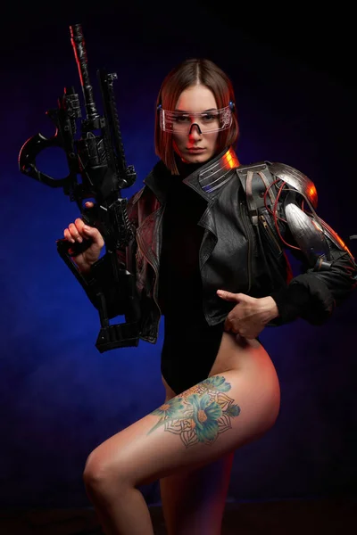 Sexy and slim woman with implant and rifle poses in dark background — Stock Photo, Image