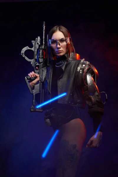 Agente femenina futurista armado con rifle posando en fondo oscuro — Foto de Stock