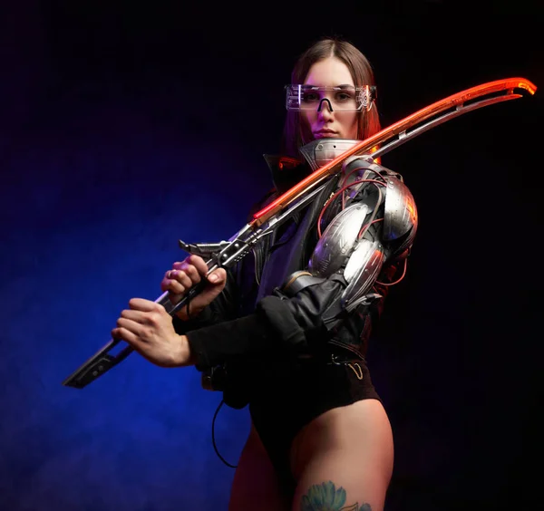 Mulher urbana e cyberpunk estilo assassino com espada posando em estúdio — Fotografia de Stock