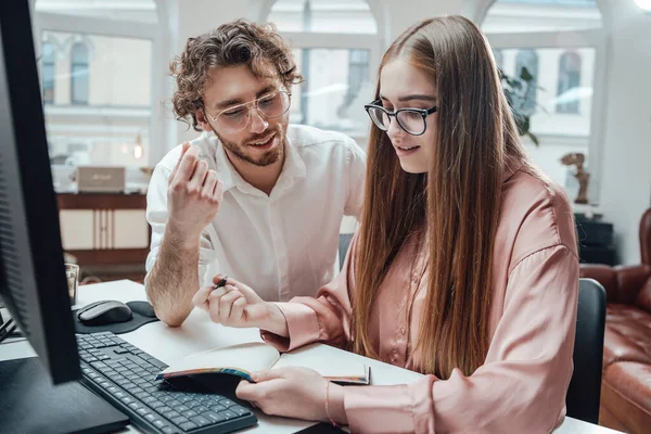 Twee vrolijke collega 's van plan zitten aan tafel met notebook — Stockfoto