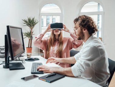 Beyaz kadın meslektaşının yanında sanal gerçeklik kulaklığından hoşlanıyor.