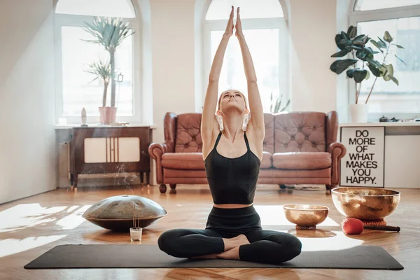 Glänsande vardagsrum och avslappnad kvinna gör yoga på mattan — Stockfoto