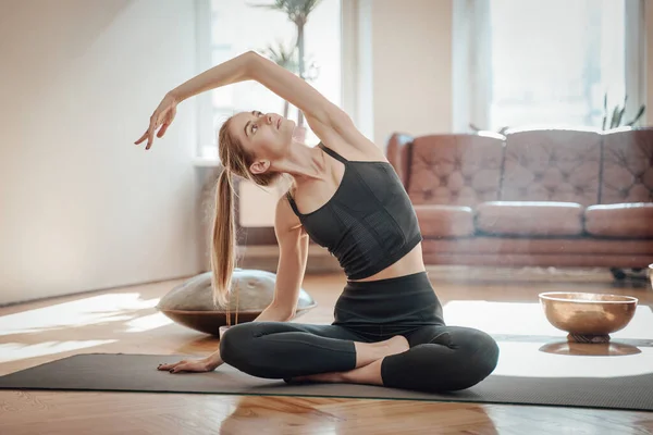 Glänsande vardagsrum och avslappnad kvinna gör yoga på mattan — Stockfoto