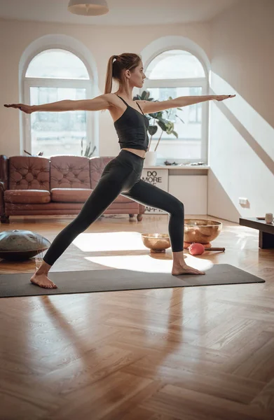 Mulher alegre em sportswear fazendo ioga no tapete no quarto — Fotografia de Stock