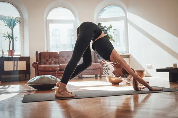 Mujer delgada caucásica haciendo ejercicio en la sala de estar con rayos de sol — Foto de Stock