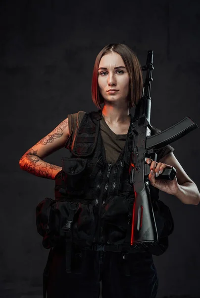 어두운 배경에서 총을 들고 있는 매력적 인 군사 소녀 — 스톡 사진