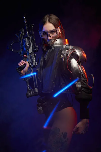 Futuristic female agent armed with rifle posing in dark background — Stock Photo, Image