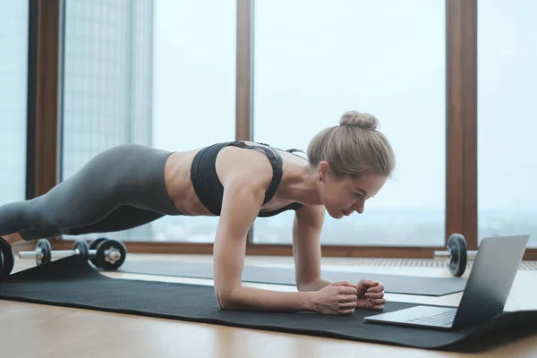 Sportiva caucasica in appartamento fare yoga con il computer portatile — Foto Stock