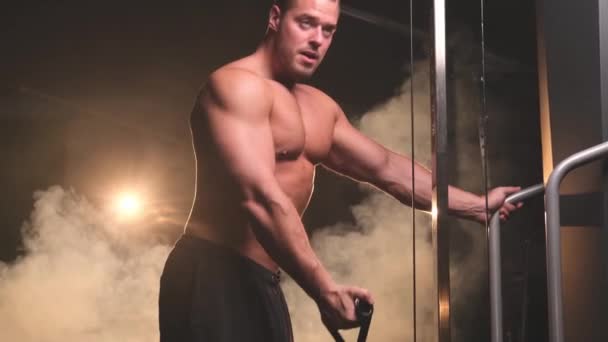 El chico atractivo y fuerte trabaja con la máquina de levantamiento de pesas pesadas en el gimnasio — Vídeo de stock