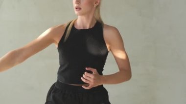 Spor kıyafetleri içinde zarif bir sarışın. Odada bacağıyla vuruyor.