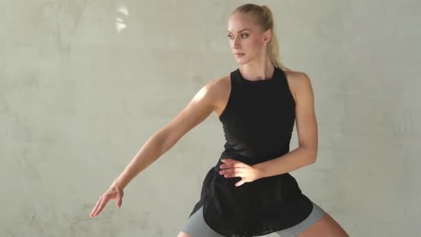 Sportovní žena s blond vlasy cvičení a zahřívání v pokoji — Stock video