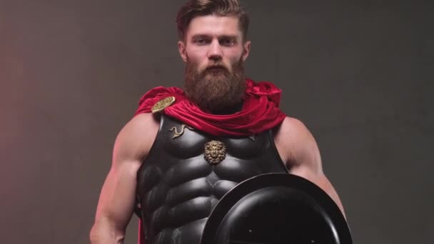 Roman armoured fighter posing in dark background with shield — Stock Video