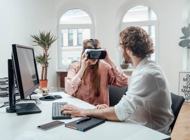 Beyaz kadın meslektaşının yanında sanal gerçeklik kulaklığından hoşlanıyor.