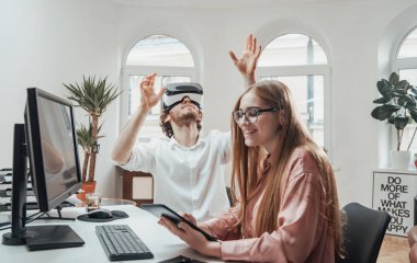 Sanal gerçeklik gözlüklü oyuncu ofis çalışanı ve tabletli kadın.
