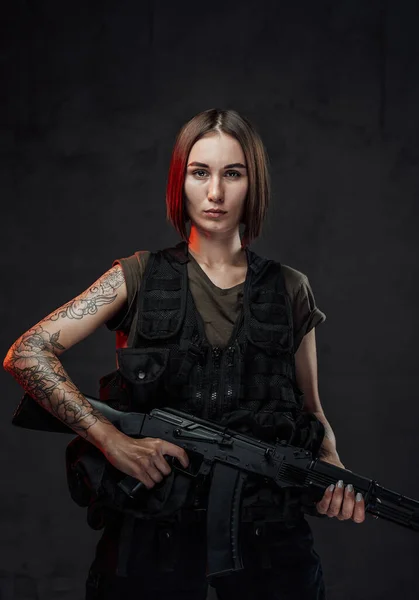 Wytatuowana wojowniczka w czarnej zbroi z karabinem szturmowym — Zdjęcie stockowe