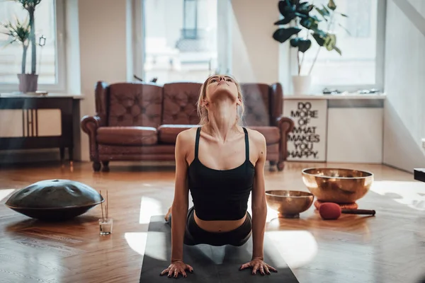 Relaxed woman works out doing yoga in bhujangasana pose in room — Stock Photo, Image