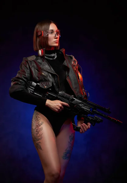 Seductive woman with naked and tattooed legs holding futuristic rifle — Stock Photo, Image