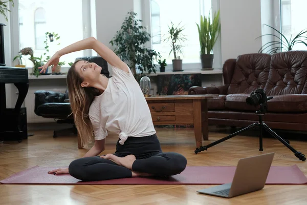Treinador de ioga feminino posa na câmera com laptop no apartamento — Fotografia de Stock