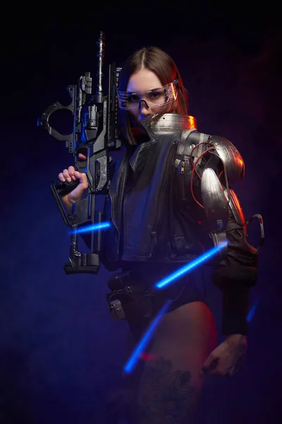 Portrait of a female mercenary with rifle in dark background with lights — Stock Photo, Image