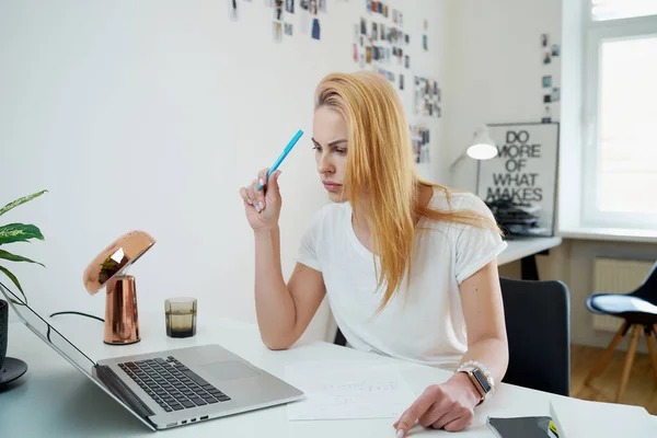Pensive vrouw werkt overdag op laptop in moderne kantoorruimte — Stockfoto