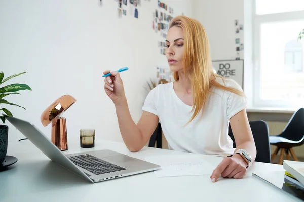 Secretária aponta para laptop sentado à mesa em seu local de trabalho — Fotografia de Stock