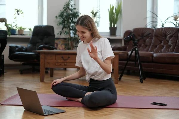 Trener jogi wita uczniów korzystających z laptopa w nowoczesnym pokoju — Zdjęcie stockowe