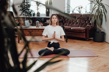 Kafkasyalı bir kadın yoga yapıyor. Sakinleştirici bir pozla modern iç mekanla odada.