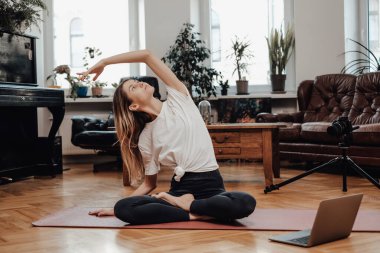 Esnek kadın modern odada dizüstü bilgisayarla poz veriyor.